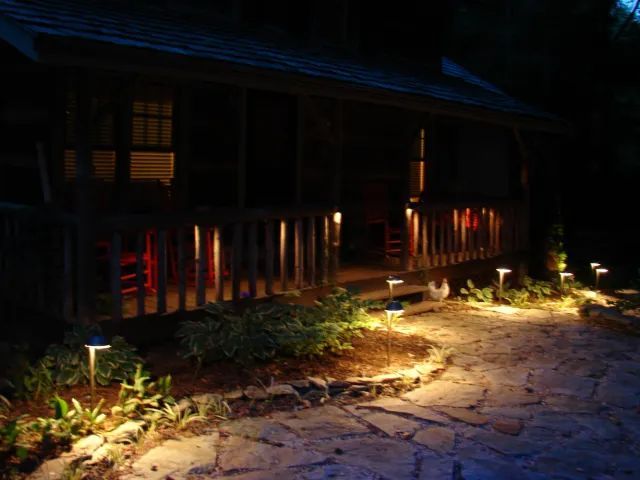 Stone path leading to a porch lit by landscape lights.