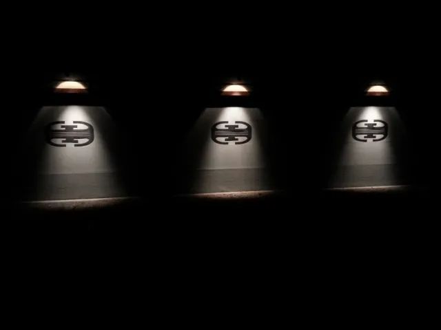Three spotlights illuminate Gucci logos against a dark backdrop.