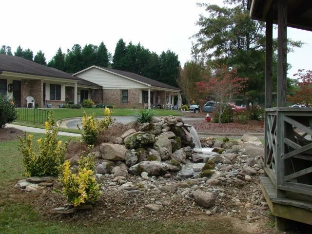 Landscaped front yard with small waterfall and residential buildings.