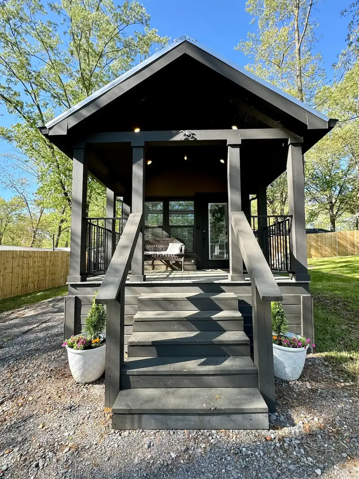 A small black house with a porch and stairs.