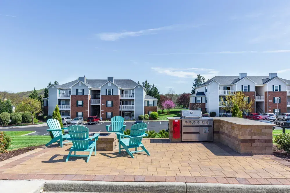 A patio with blue chairs and a grill in front of a building at Glade Creek, VA.