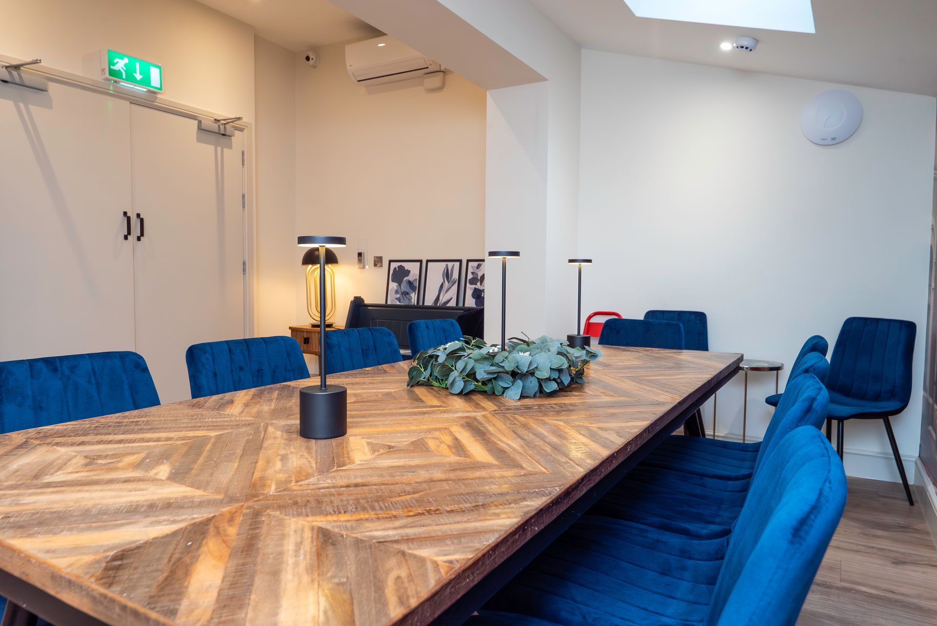 Long wooden table with blue velvet chairs in a meeting room.