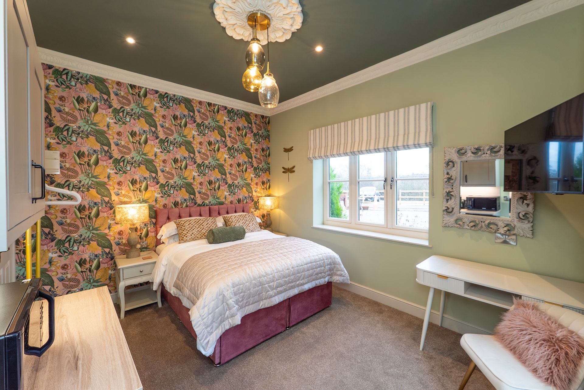 Bedroom with floral wallpaper, bed, desk, window, and olive green walls.