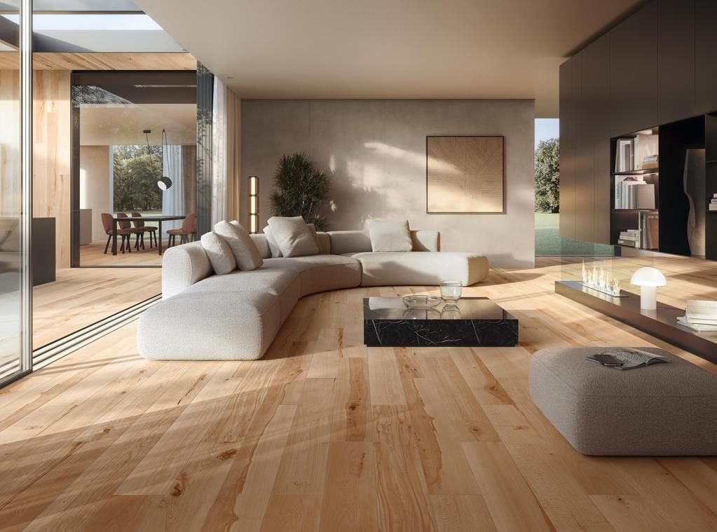 Soggiorno moderno con pavimento in legno chiaro, un grande divano curvo, tavolino da caffè e pianta aperta con vista sull'esterno.