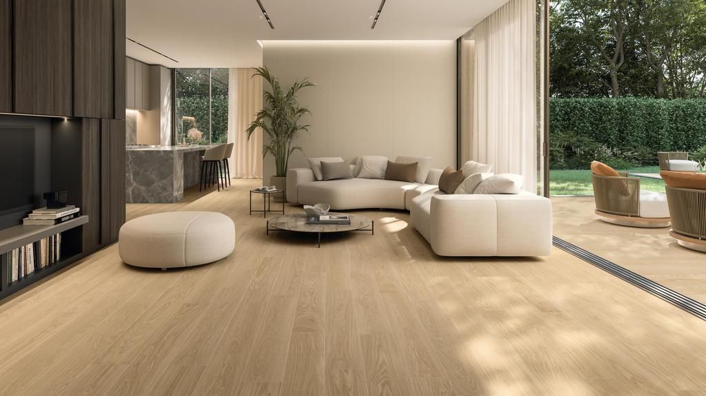 Soggiorno moderno a pianta aperta con pavimento in legno chiaro, mobili beige, tavolino centrale e vista sul patio esterno.