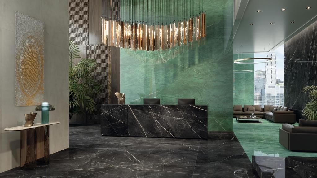 La hall di un hotel moderno è caratterizzata da un bancone della reception in marmo nero, un'ampia parete verde decorativa e un lampadario di cristallo dorato.
