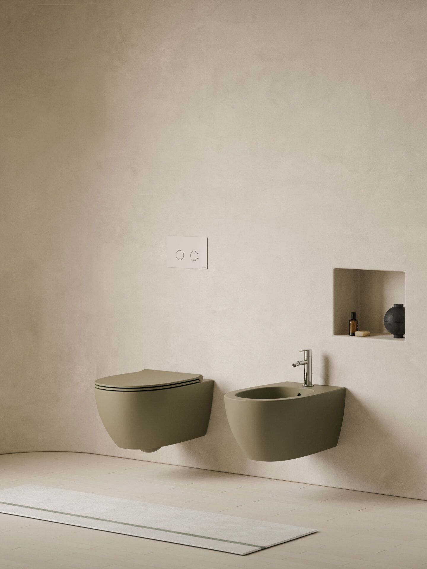 WC e bidet sospesi di colore verde oliva, in un bagno minimalista dai toni beige con nicchia a muro incassata.