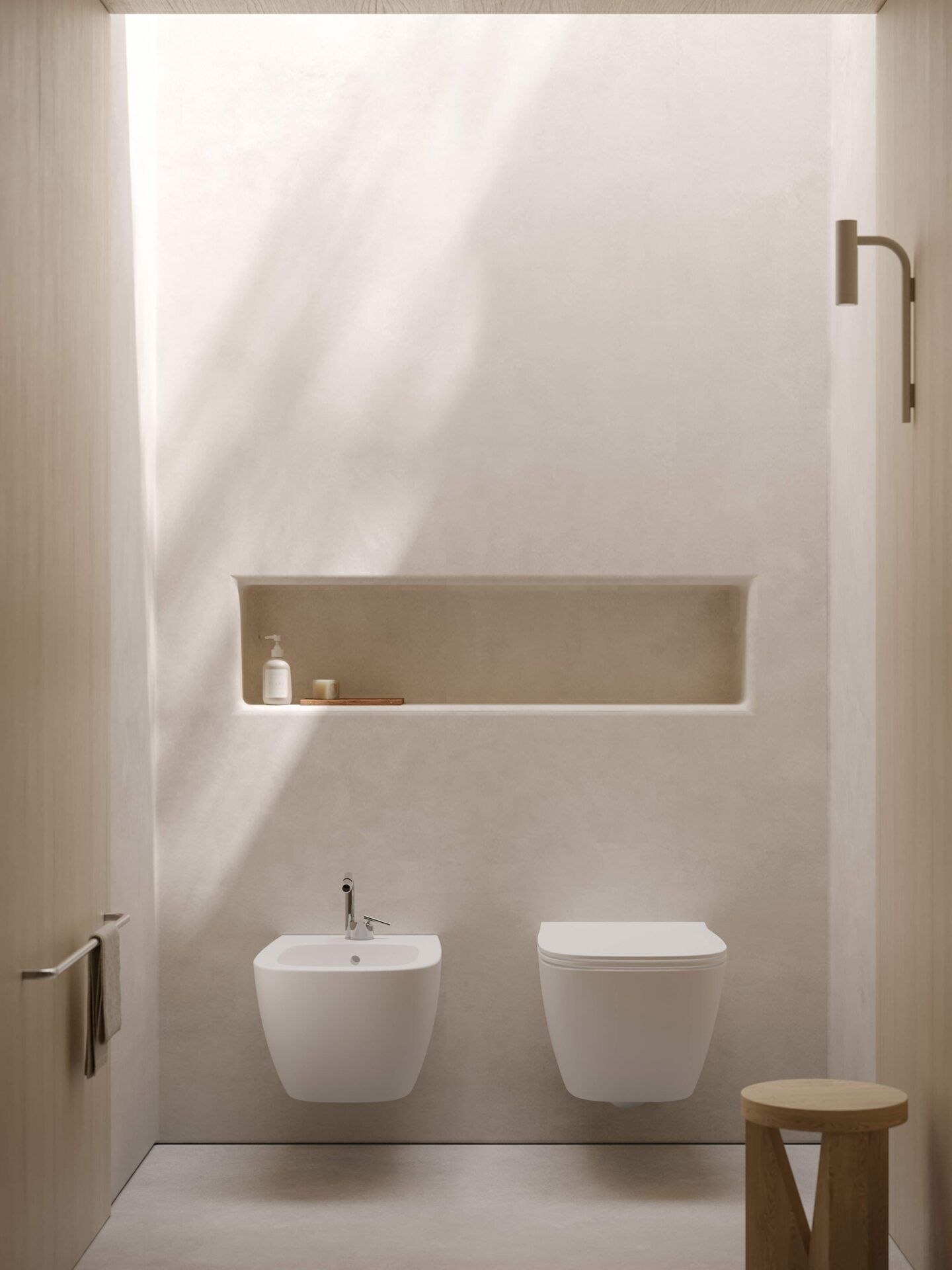 Un bagno minimalista con pareti beige, bidet e WC sospesi, una nicchia a muro e uno sgabello in legno.