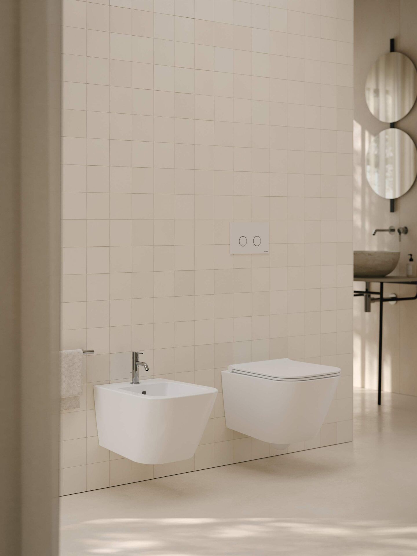 Bidet e WC a parete in un bagno moderno e minimalista con pareti rivestite con piastrelle beige neutre.