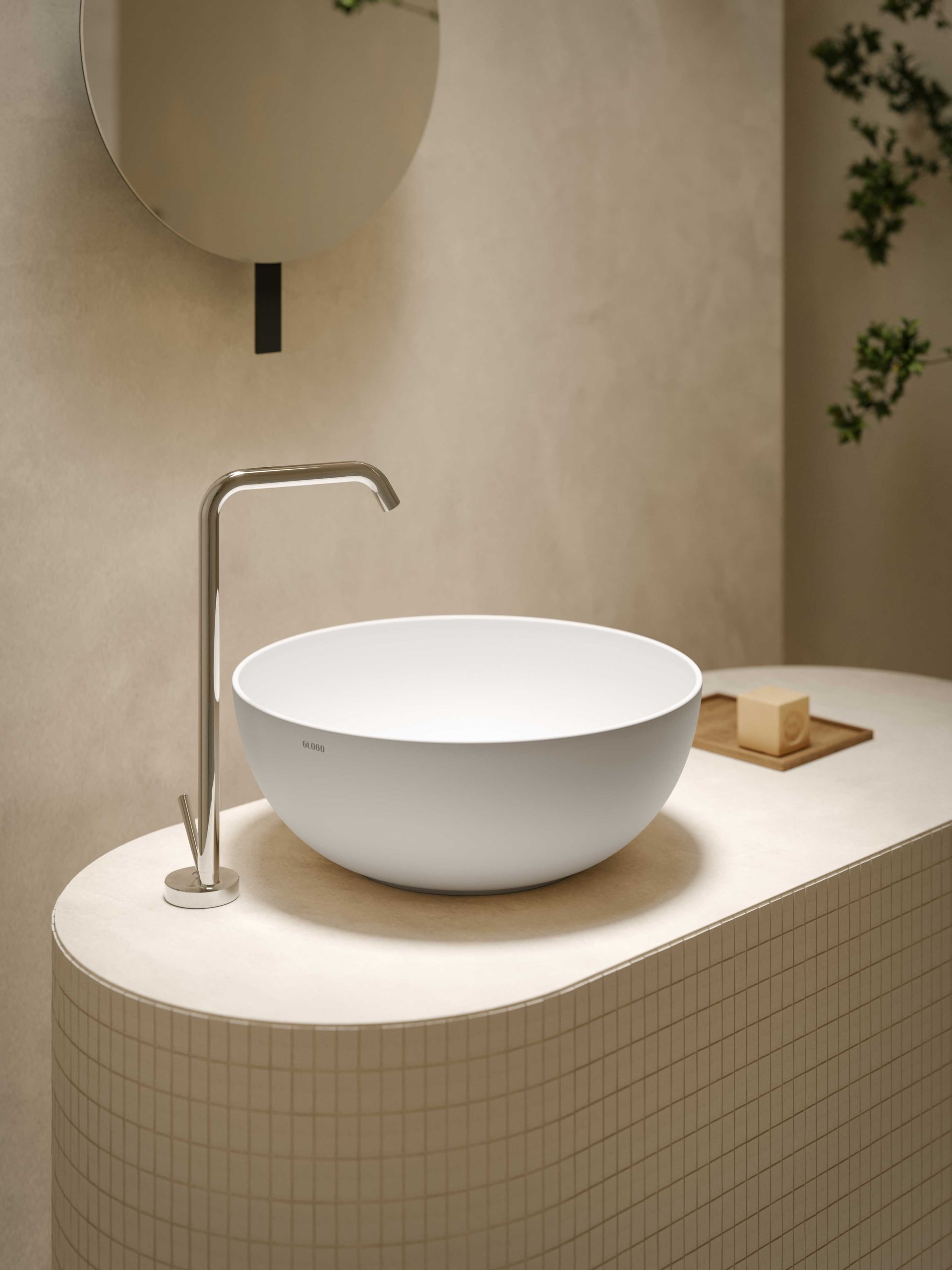 In un bagno moderno, un lavabo a ciotola bianco minimalista con un rubinetto alto color argento, posizionato sopra un mobiletto con piastrelle chiare e dalla texture particolare.