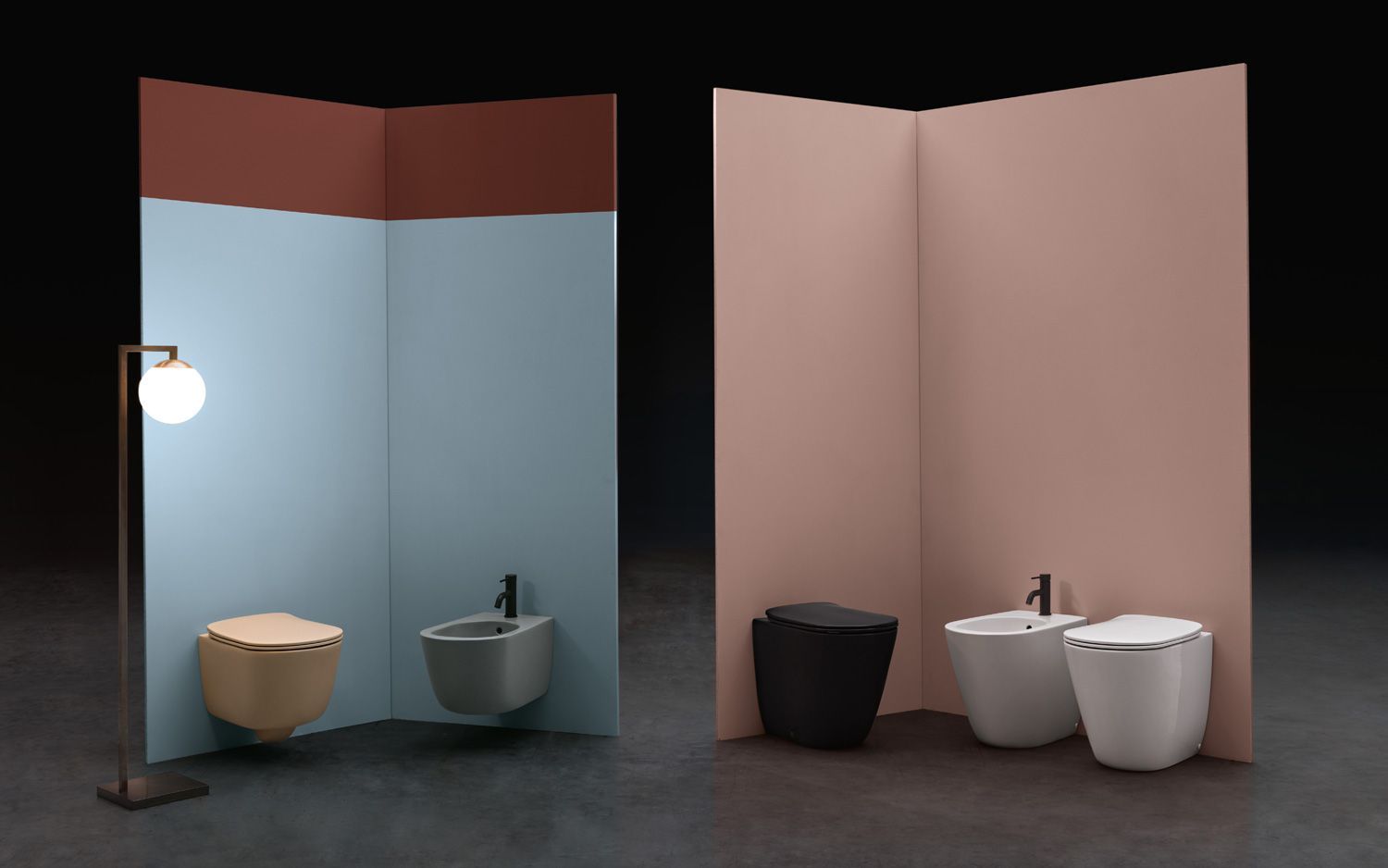In un moderno showroom, due set di WC e bidet a parete sono esposti contro pareti angolari azzurre e rosa.