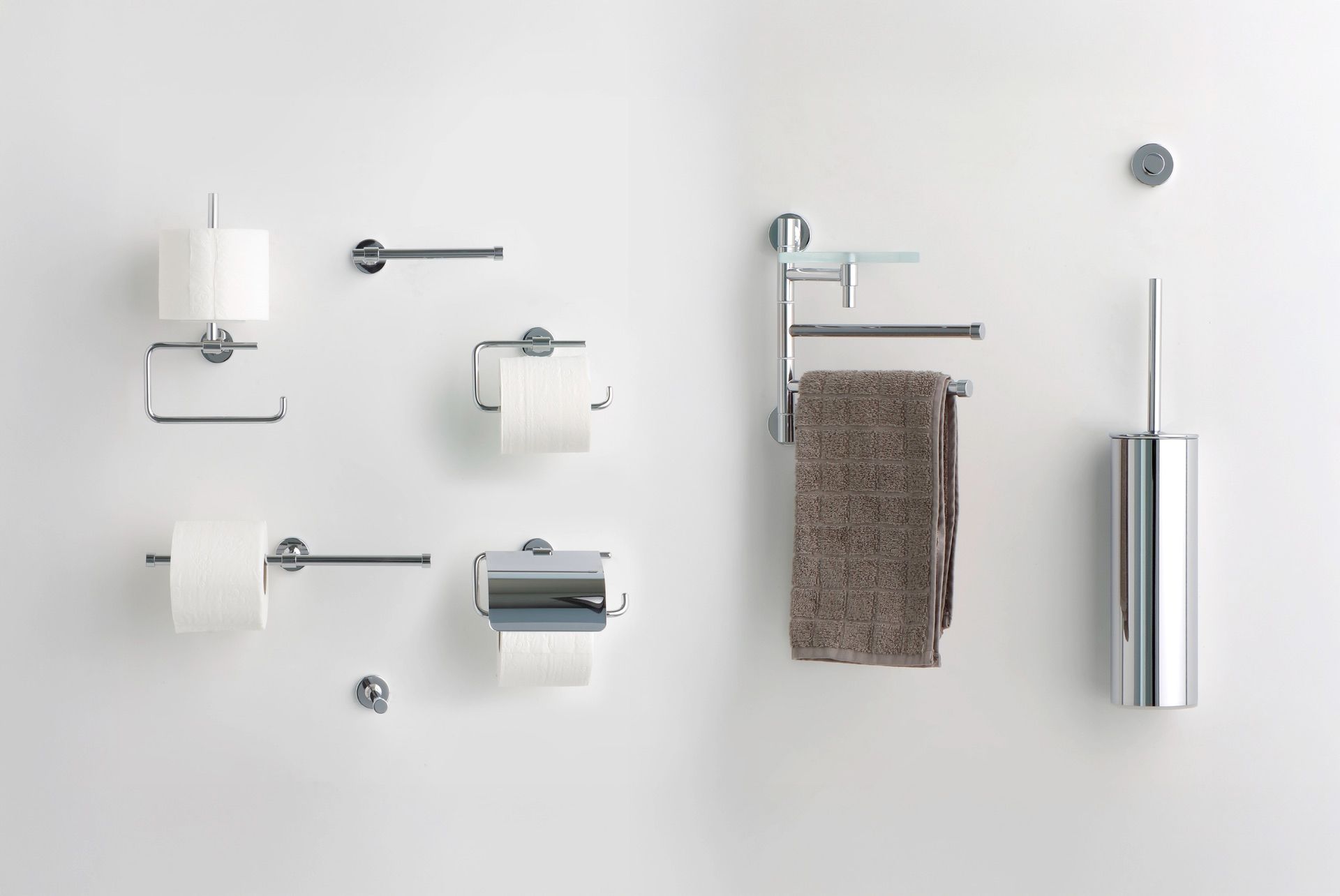 Una varietà di accessori da bagno in cromo lucido, tra cui porta carta igienica, portasciugamani e un set di scopini per WC.