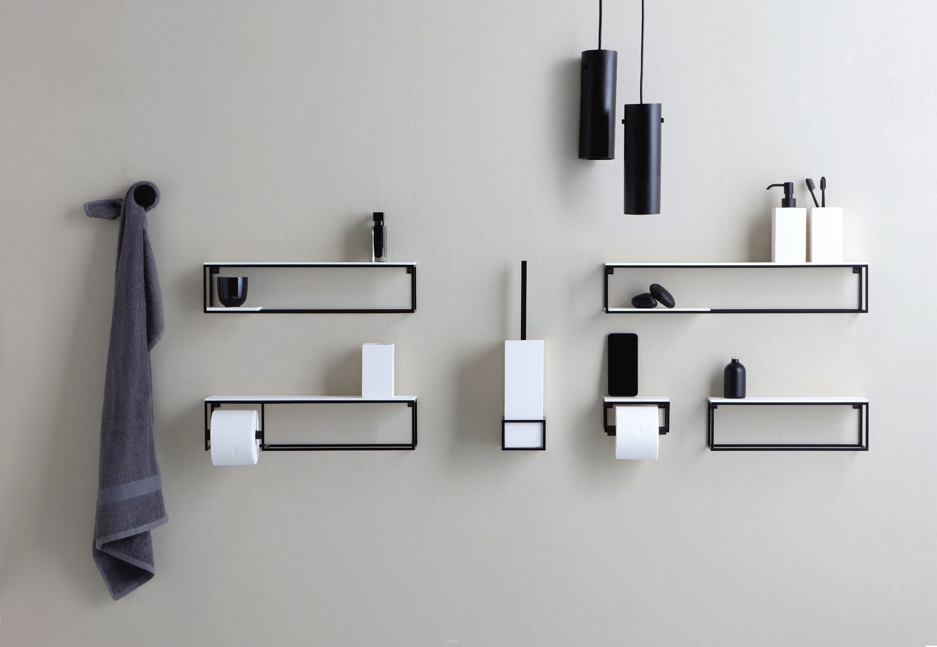 Una moderna soluzione per la parete del bagno, con mensole portaoggetti in bianco e nero, un gancio per l'asciugamano, portarotoli di carta igienica e luci.