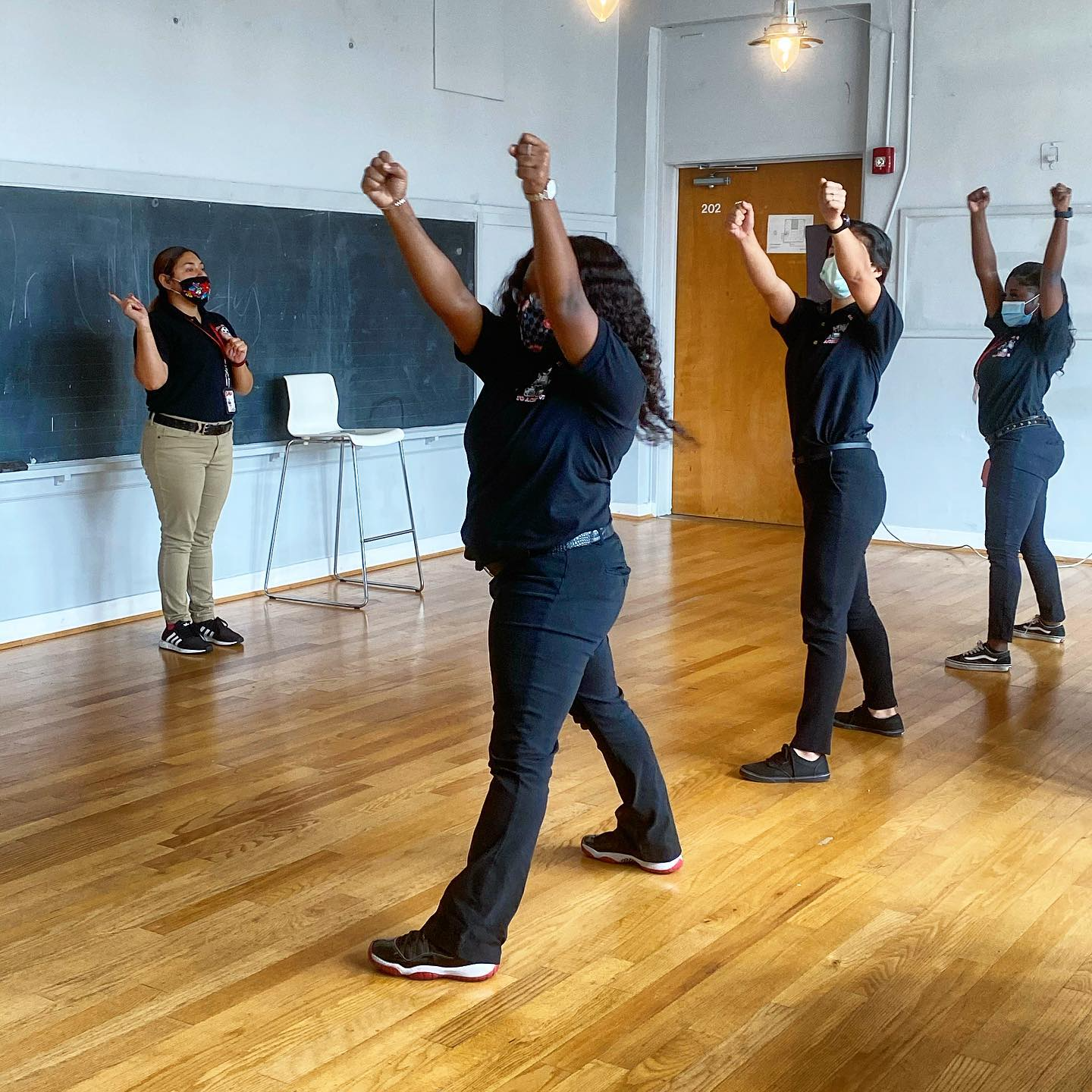 A group of people are dancing in a room with their arms in the air