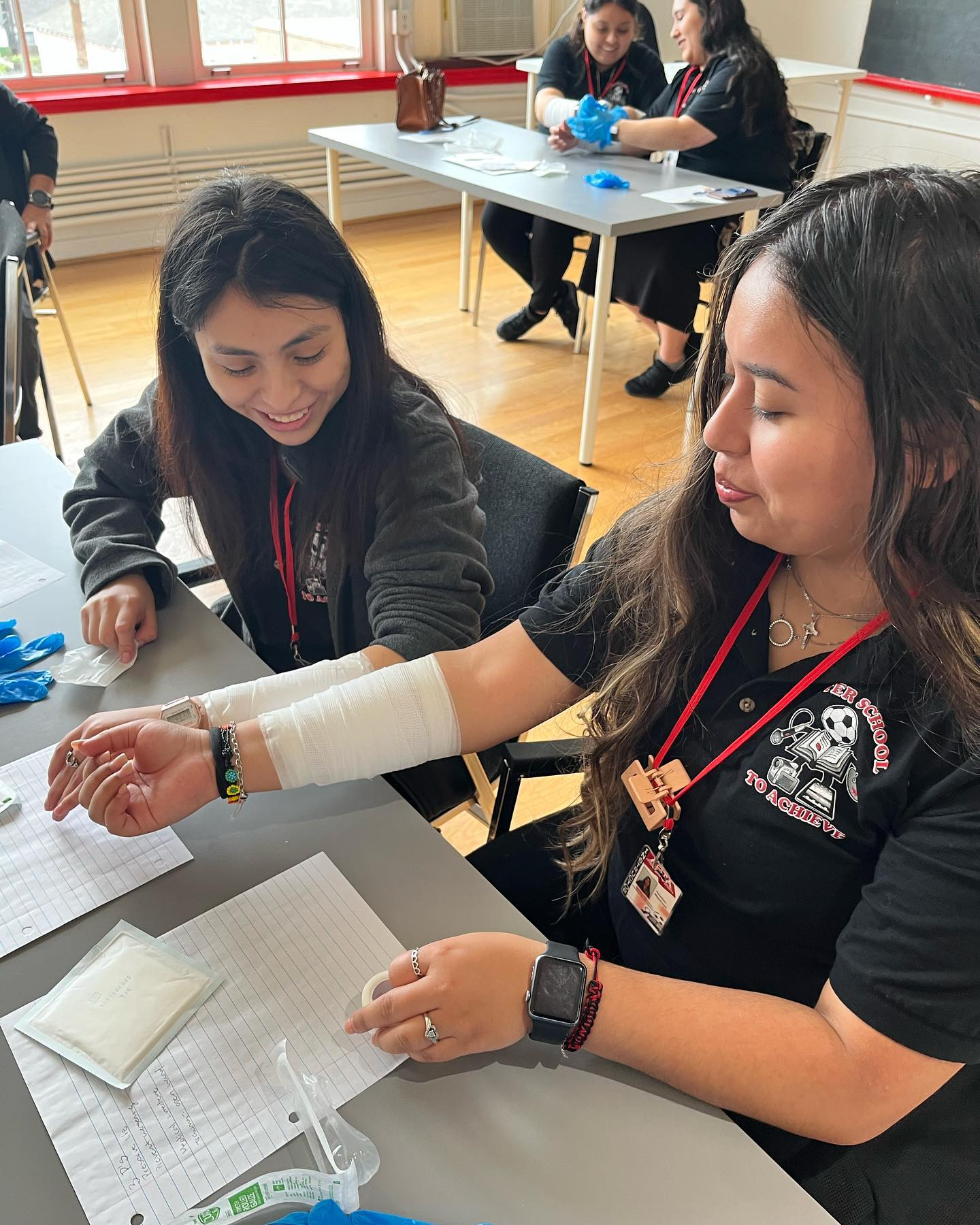 Two women are sitting at a table with a bandaged arm.