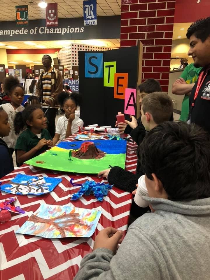 A group of children are sitting around a table with a sign that says steam