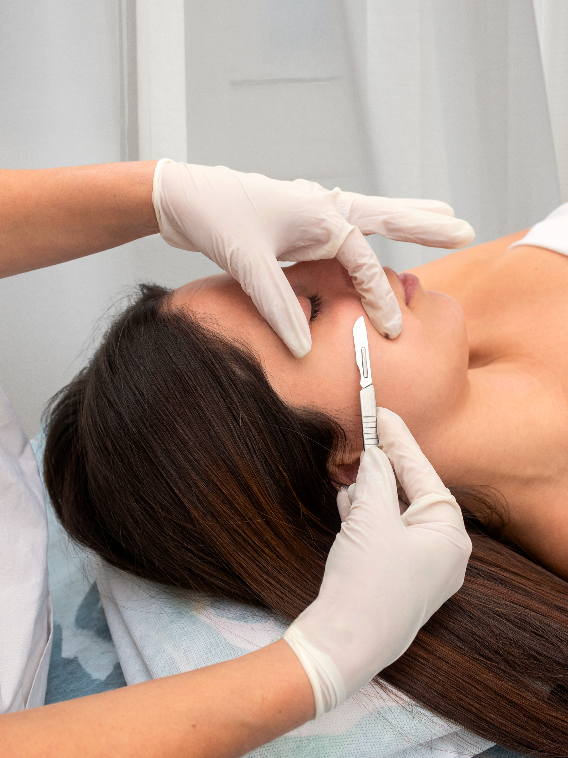 A woman is laying on a bed getting a facial treatment.