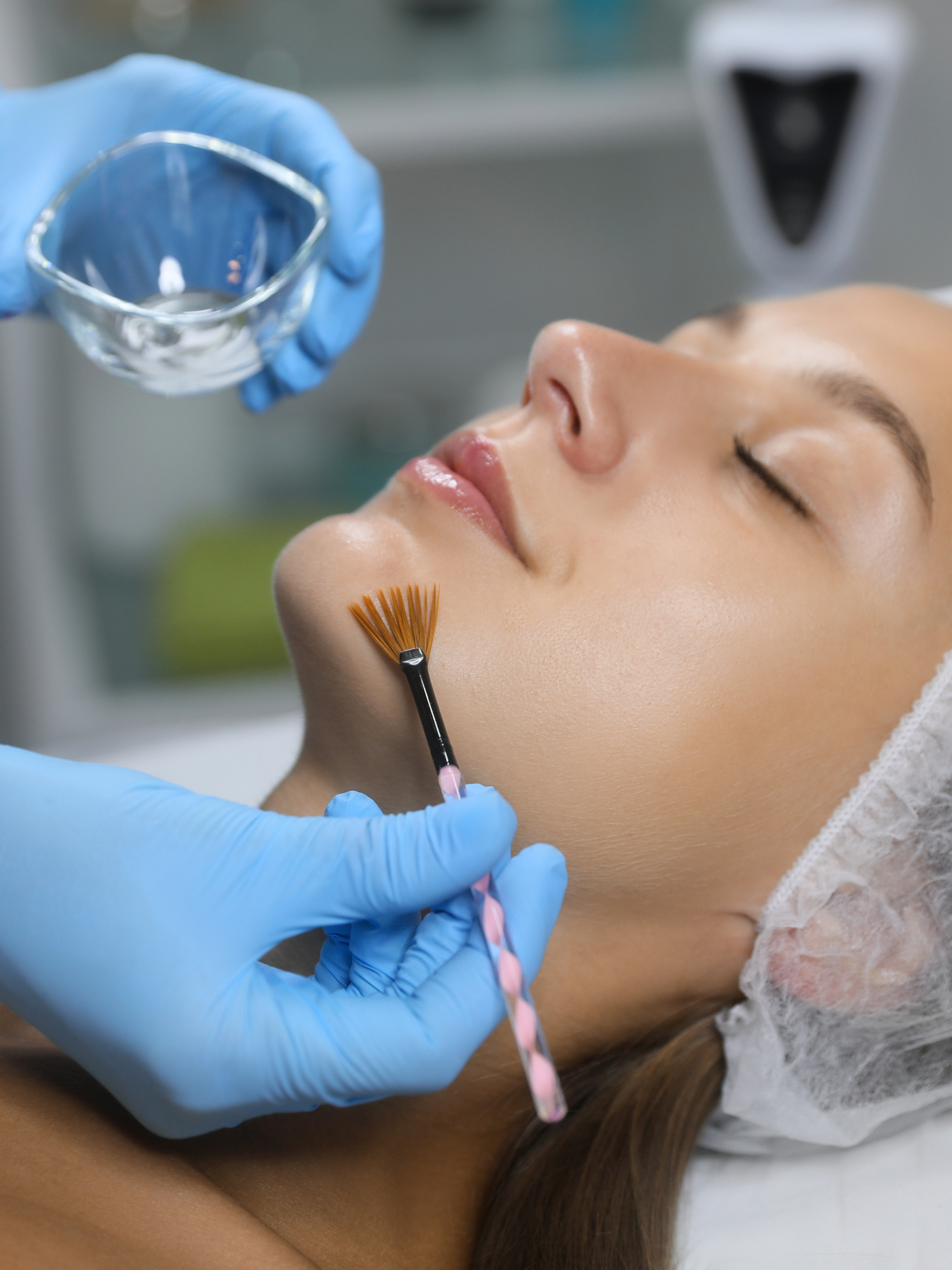 A woman is getting a facial treatment with a brush