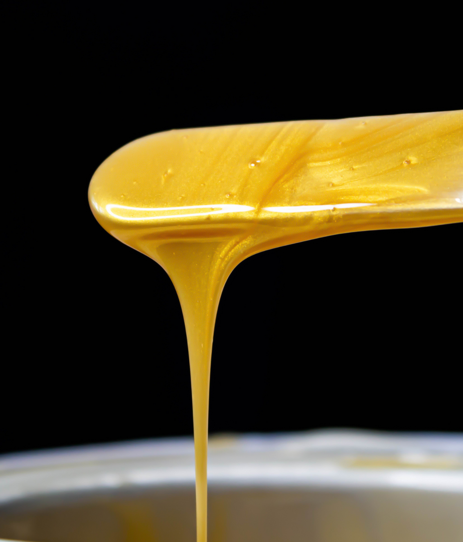A close up of a spoon of honey pouring into a bowl.