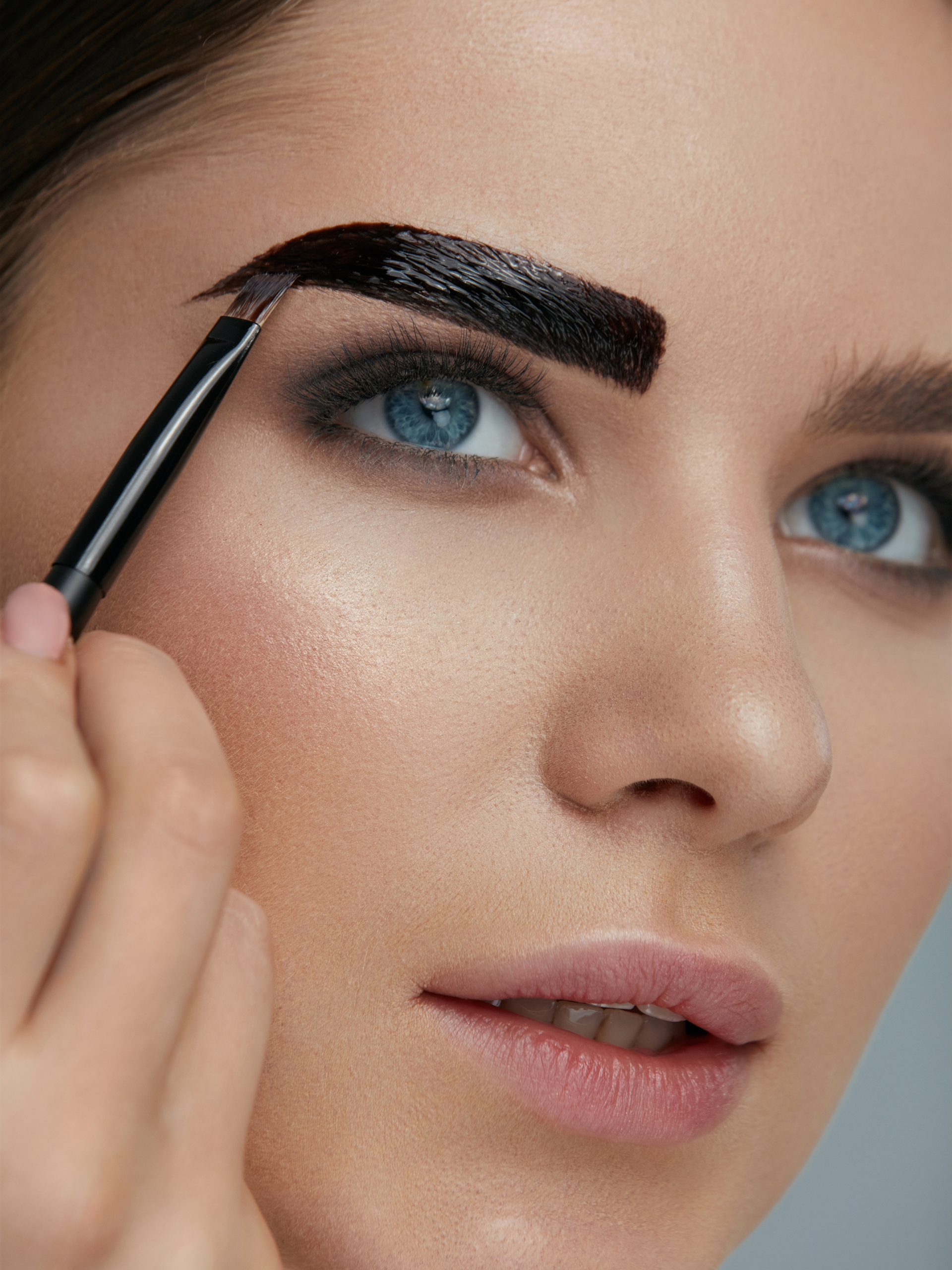 A woman is applying black eyebrow dye to her eyebrows.