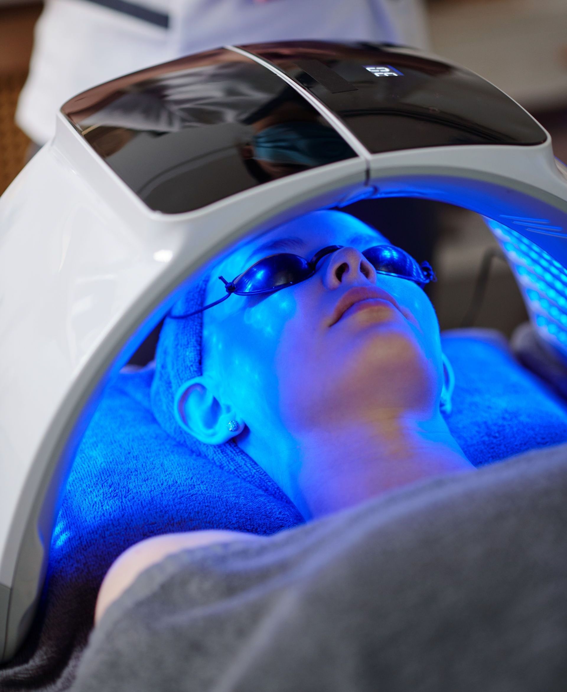 A woman is getting a blue light treatment on her face