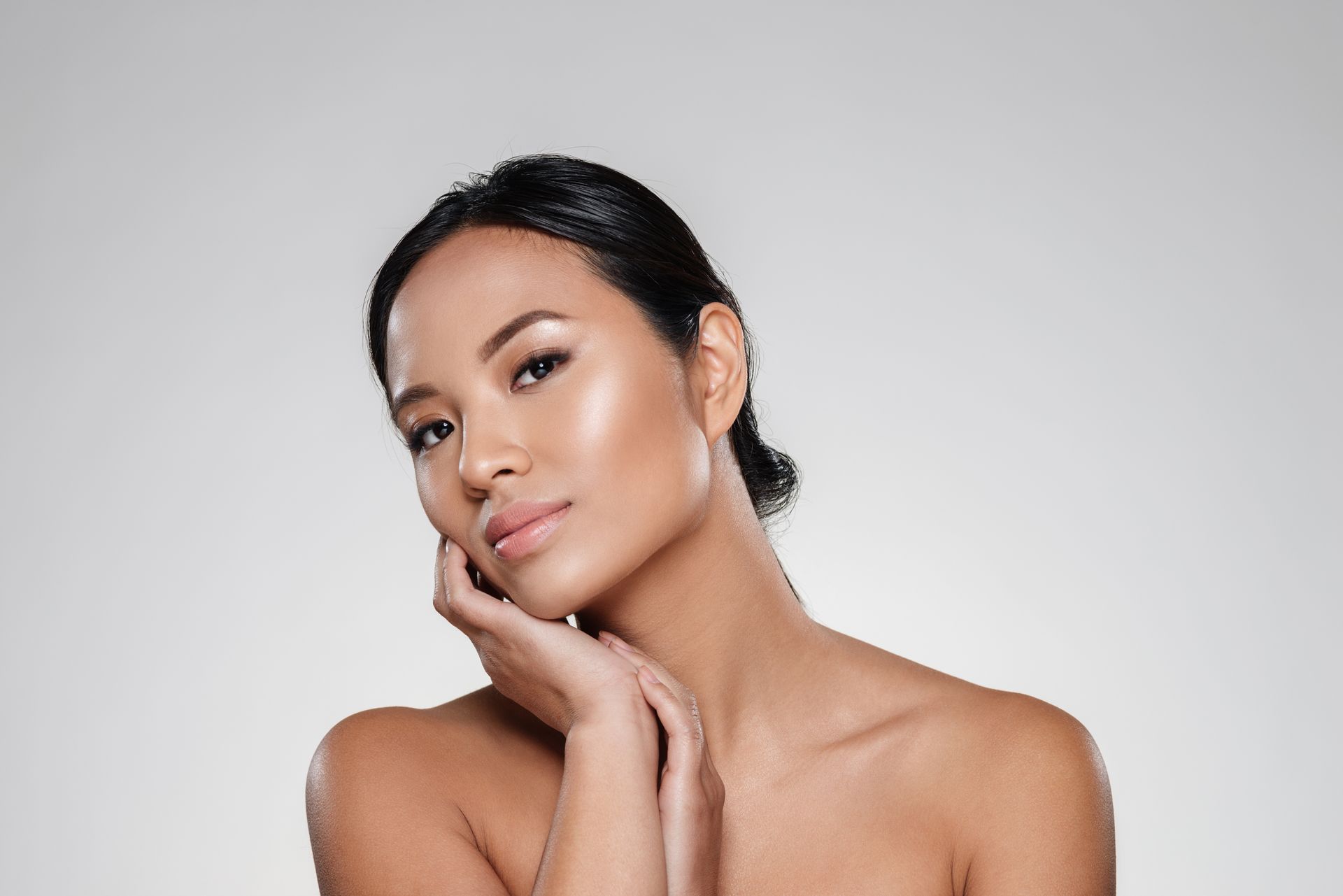 A woman is touching her face with her hand and looking at the camera.