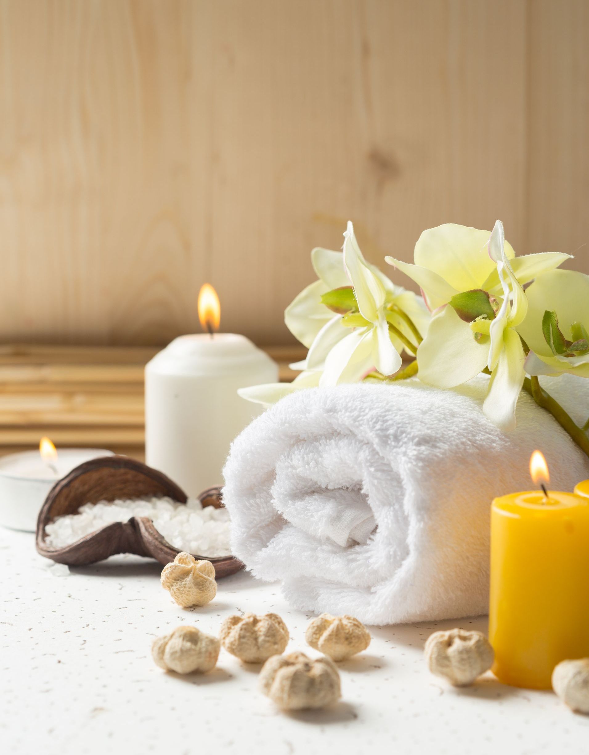 A towel , candles , and flowers are on a table.
