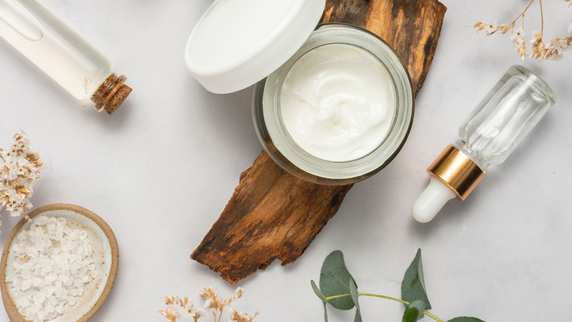 A jar of cream is sitting on top of a piece of wood.