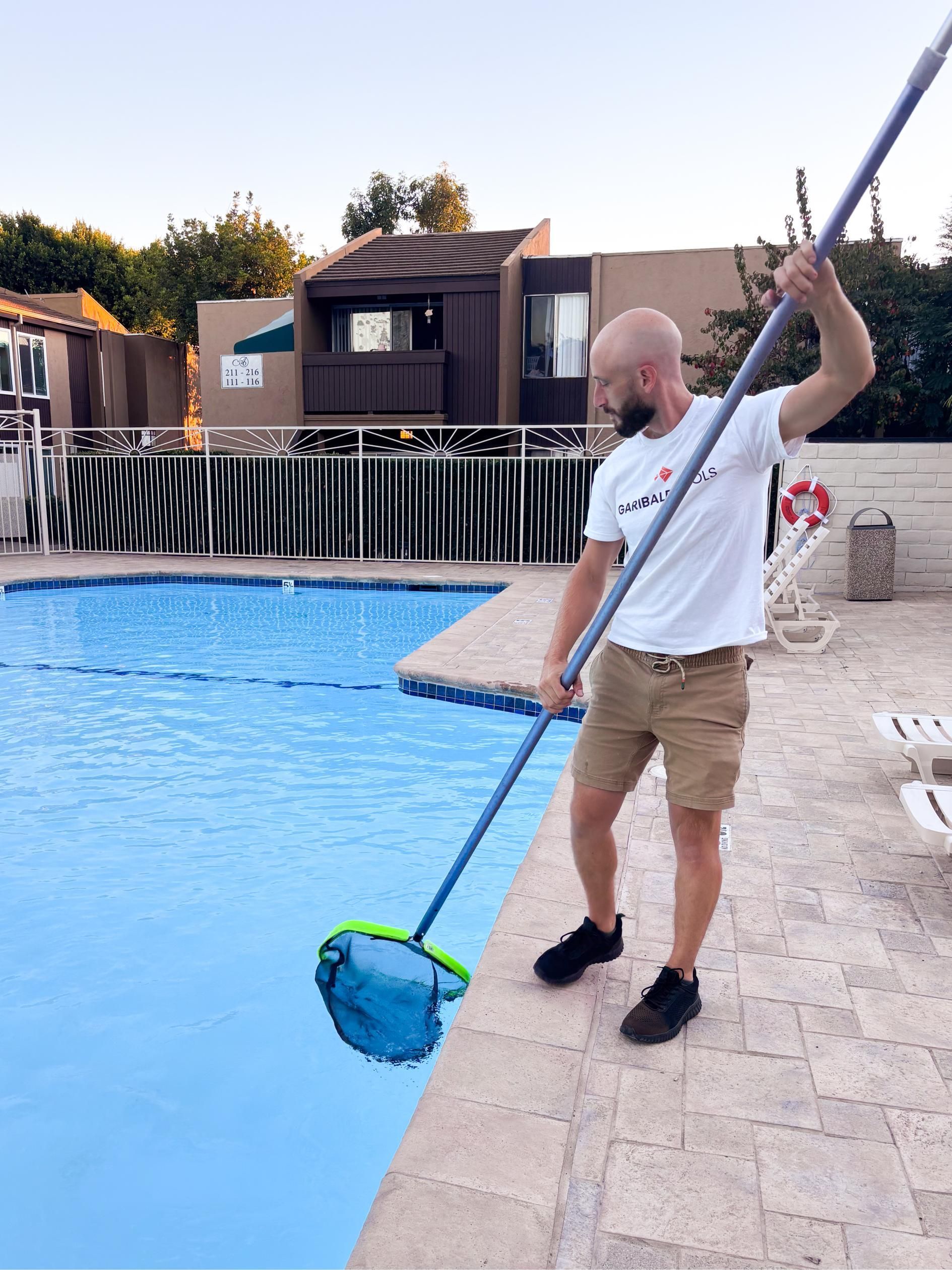 A man is cleaning a swimming pool with a net.