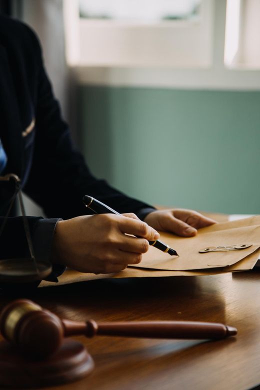 a man is sitting at a table writing on a piece of paper with a pen .