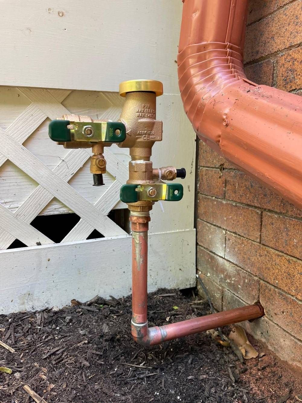 A copper pipe is attached to a brick wall.