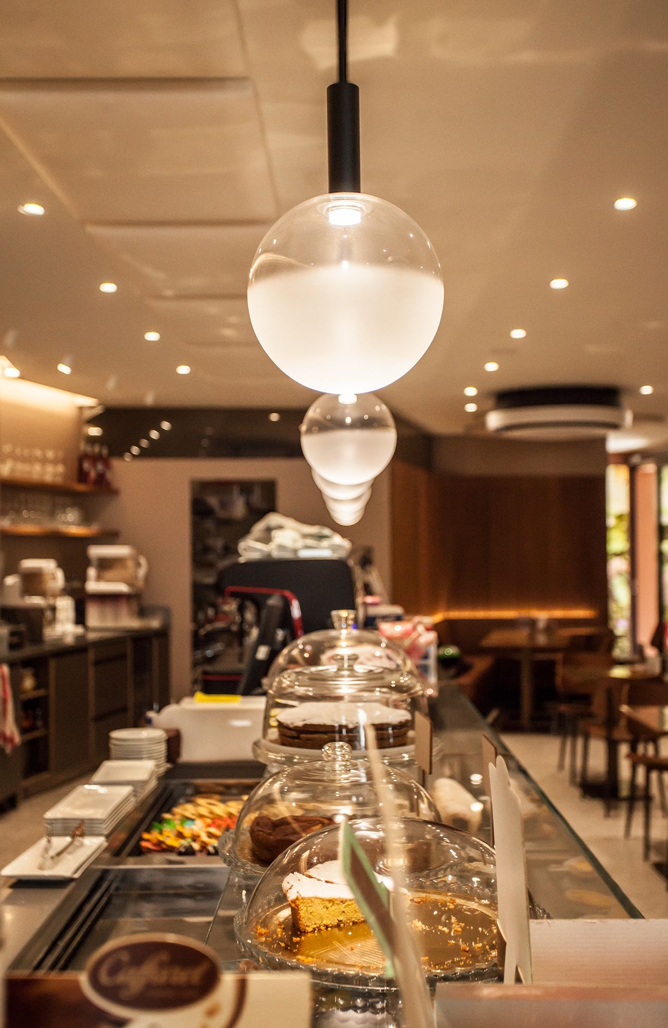 Bancone buffet con vassoi coperti in un interno di ristorante illuminato da luci calde.