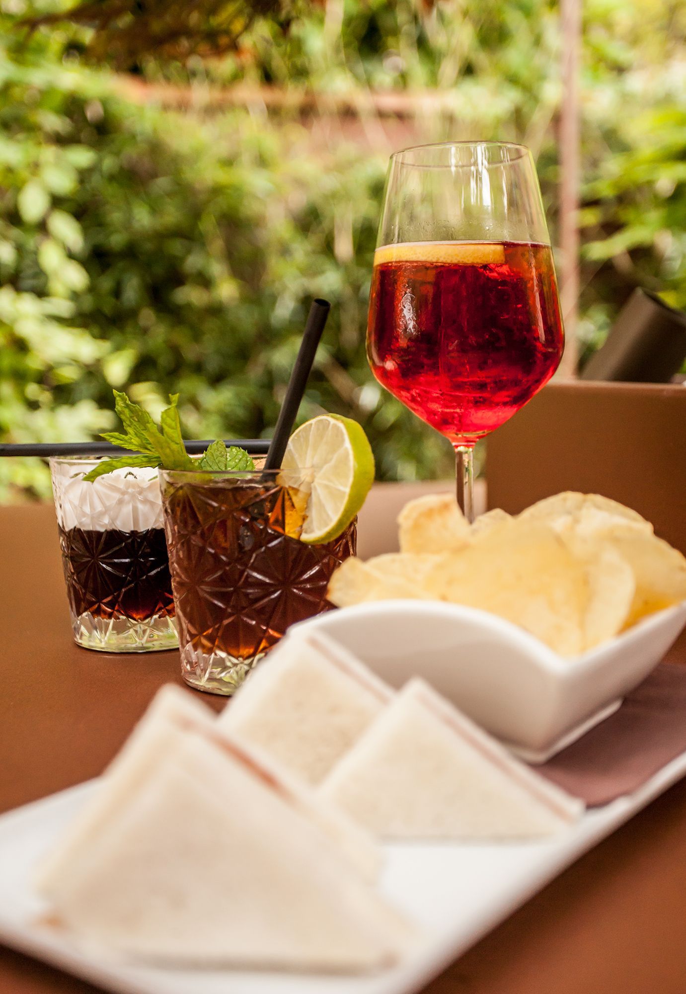 Vino e cocktail al limone su un tavolo all'aperto, accompagnati da patatine e pane pita.