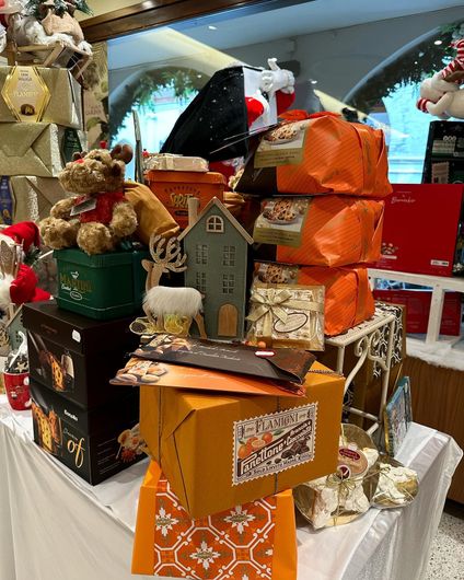In un negozio, scatole regalo natalizie e peluche impilati su un tavolo.