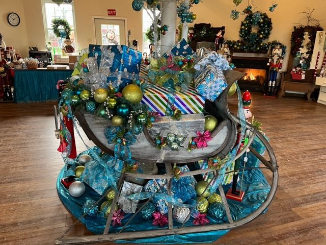 A sleigh decorated for christmas is sitting on a wooden floor in a room.