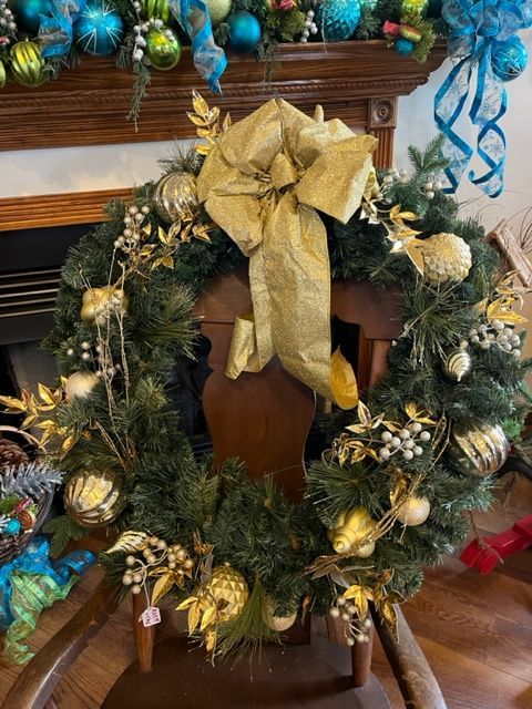 A christmas wreath is sitting on a chair in front of a fireplace.