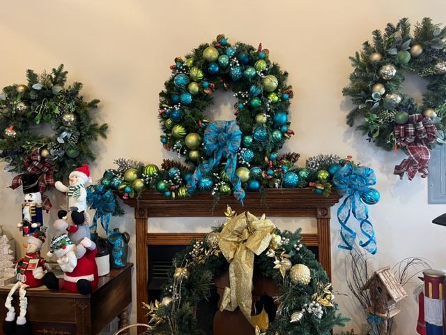 Three christmas wreaths are hanging on a wall above a fireplace.