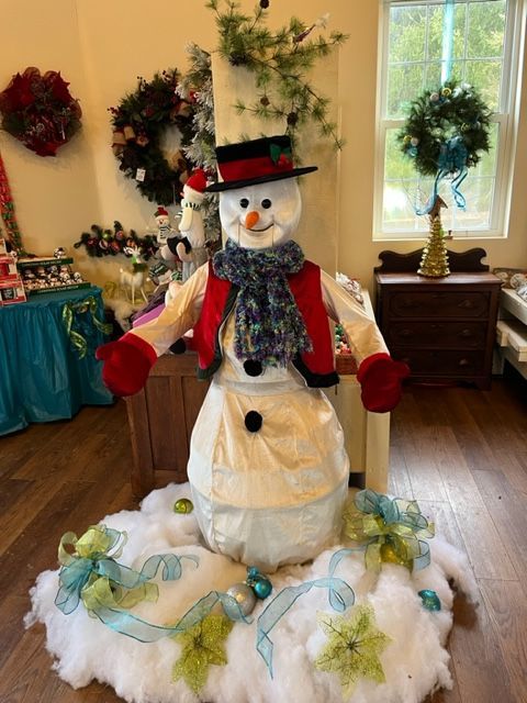 A large snowman is standing in a room with christmas decorations.