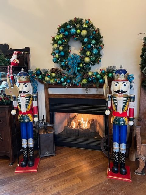 Two nutcrackers are standing in front of a fireplace decorated for christmas.