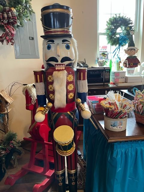 A large nutcracker is sitting on a rocking horse in a room.