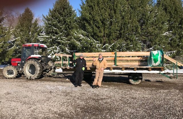 Two men are standing next to a trailer with a tractor pulling it.