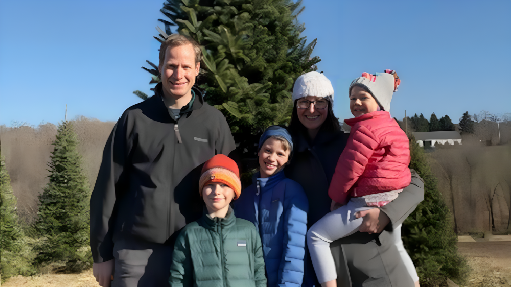 A family is posing for a picture in front of a christmas tree.