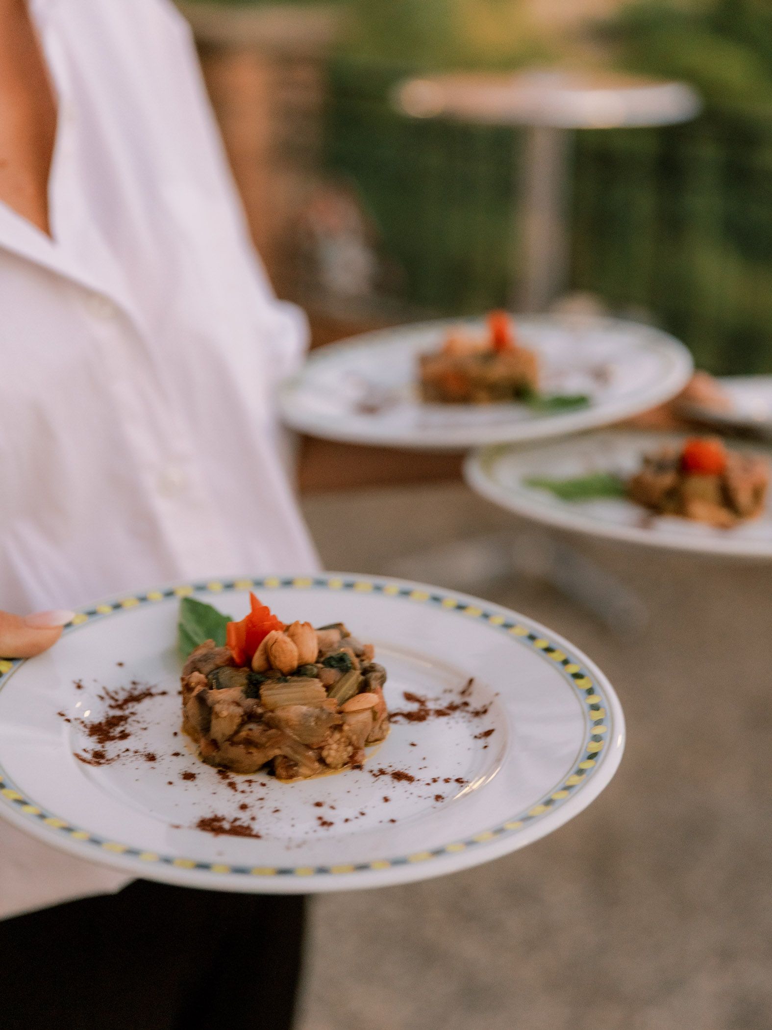 Une personne tenant une assiette avec une petite entrée à la terrasse d'un restaurant