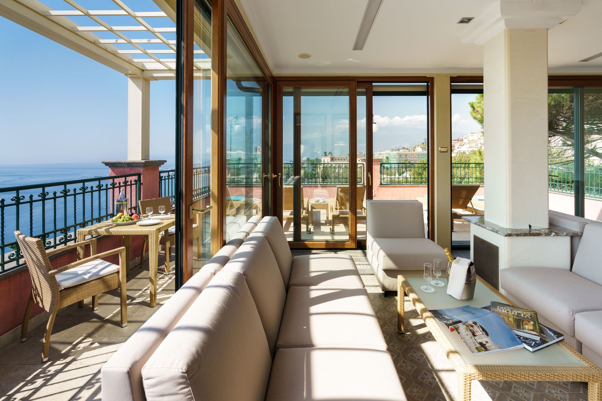Helle Terrasse am Meer mit beigen Sofas, Glastüren und Meerblick
