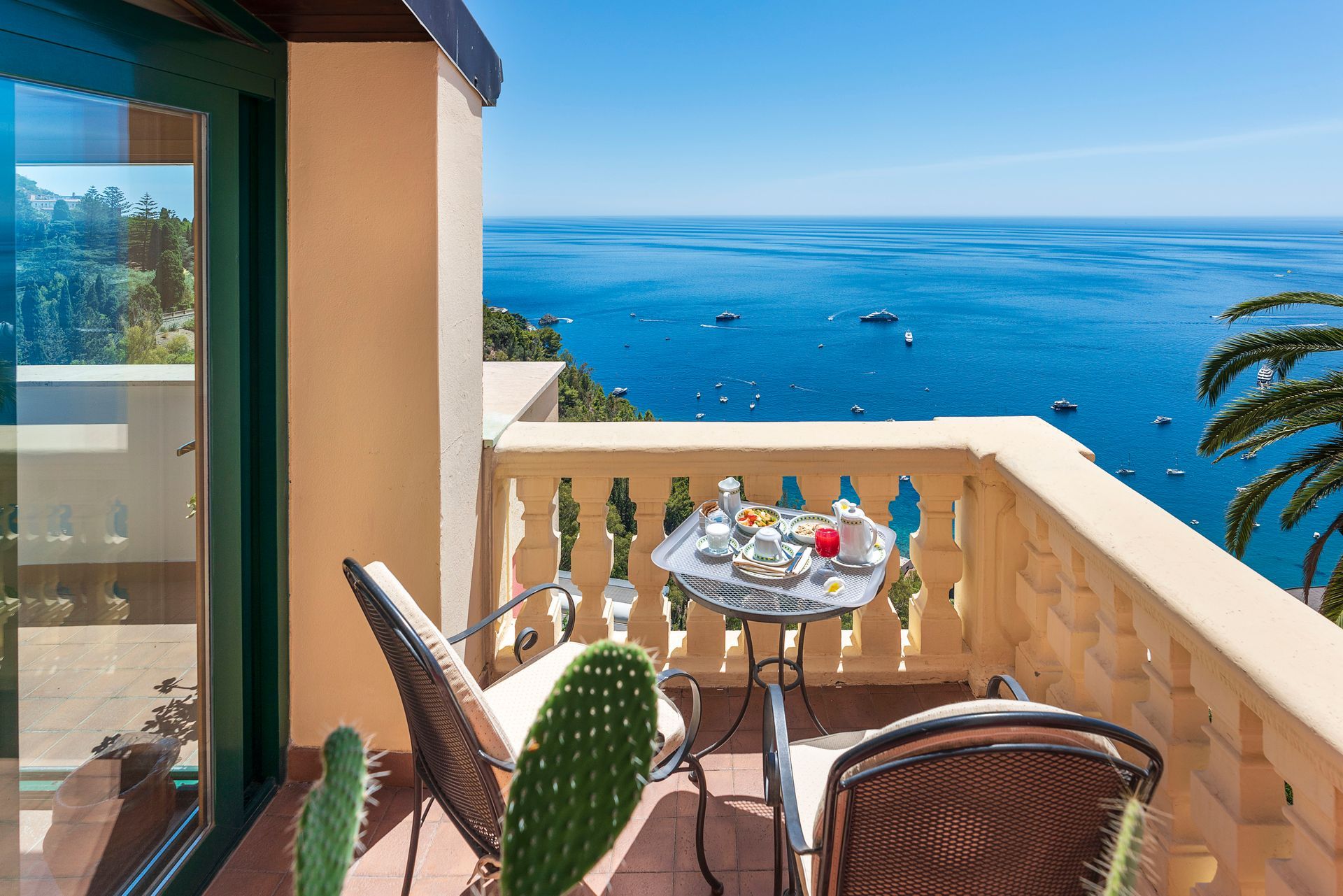 Balkon mit Tisch und Stühlen mit Blick auf ein strahlend blaues Meer unter klarem Himmel