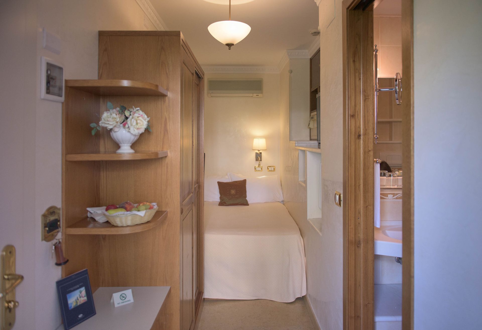 Gemütliches Schlafzimmer mit Bett, Holzregalen und Zugang zu einem kleinen angrenzenden Badezimmer