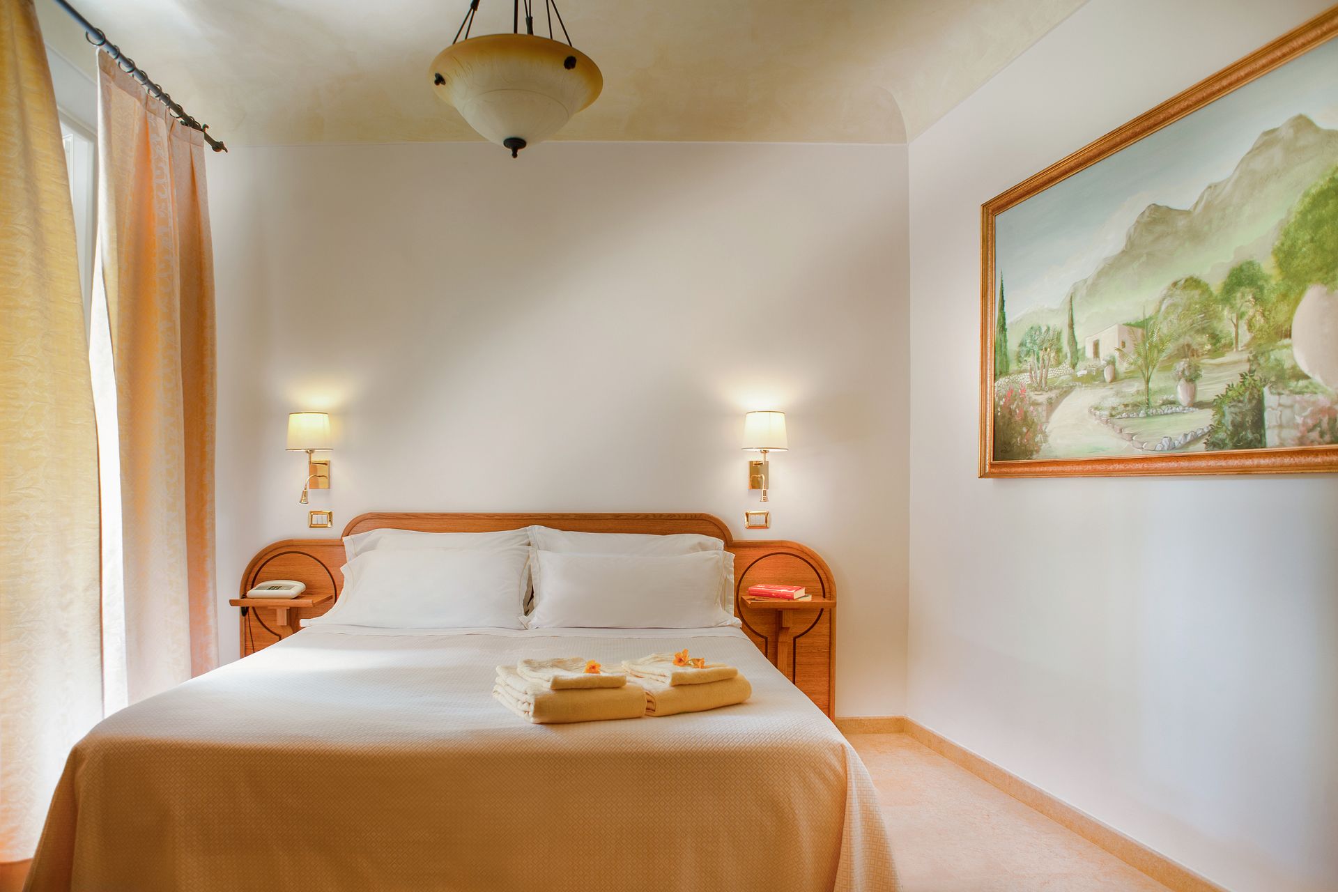 Helles Schlafzimmer mit ordentlich gemachtem Bett, Nachttischlampen und einem gerahmten Landschaftsgemälde