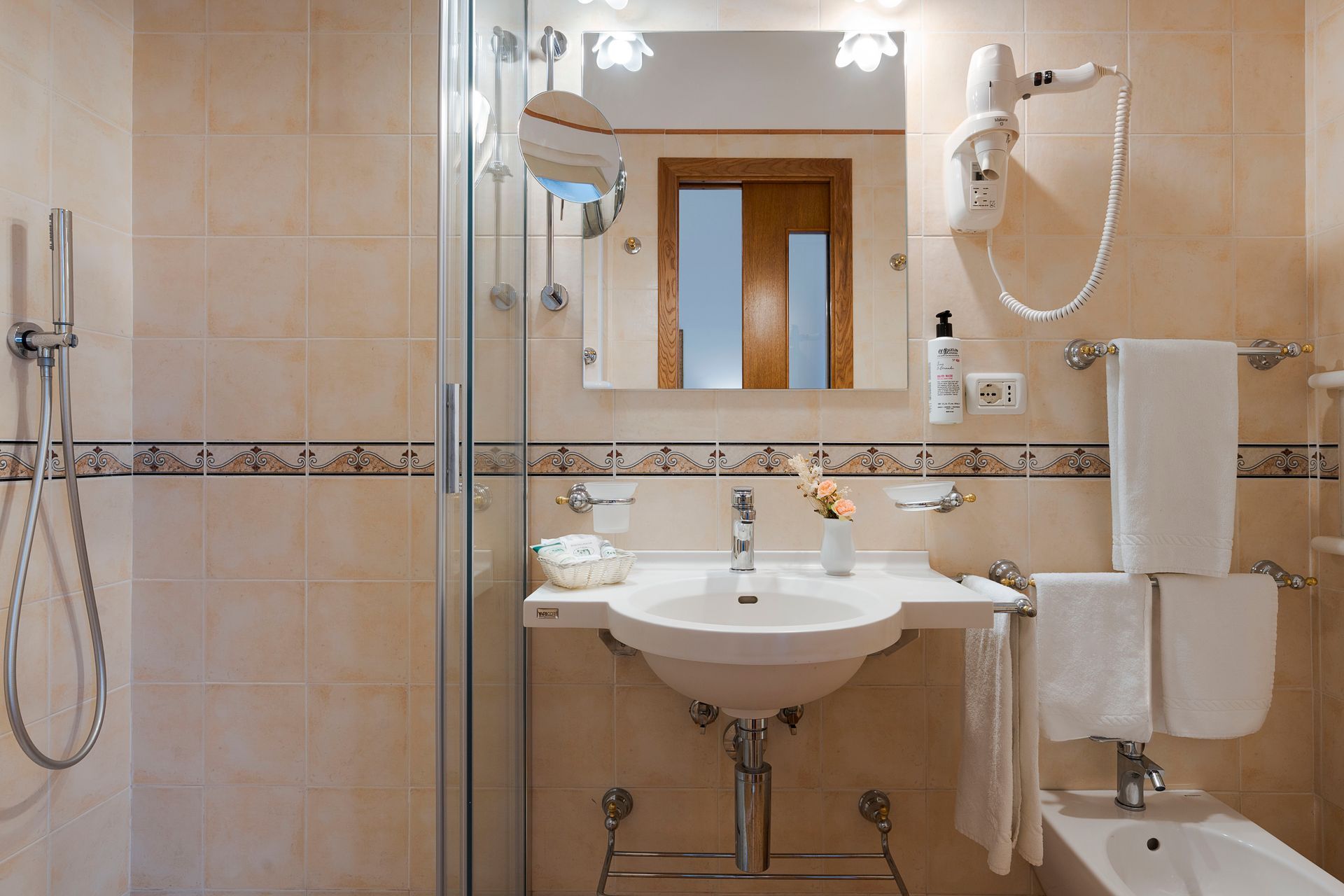 Barrierefreies Badezimmer mit ebenerdiger Dusche, Waschbecken, Spiegel, Haltegriffen und Handtüchern