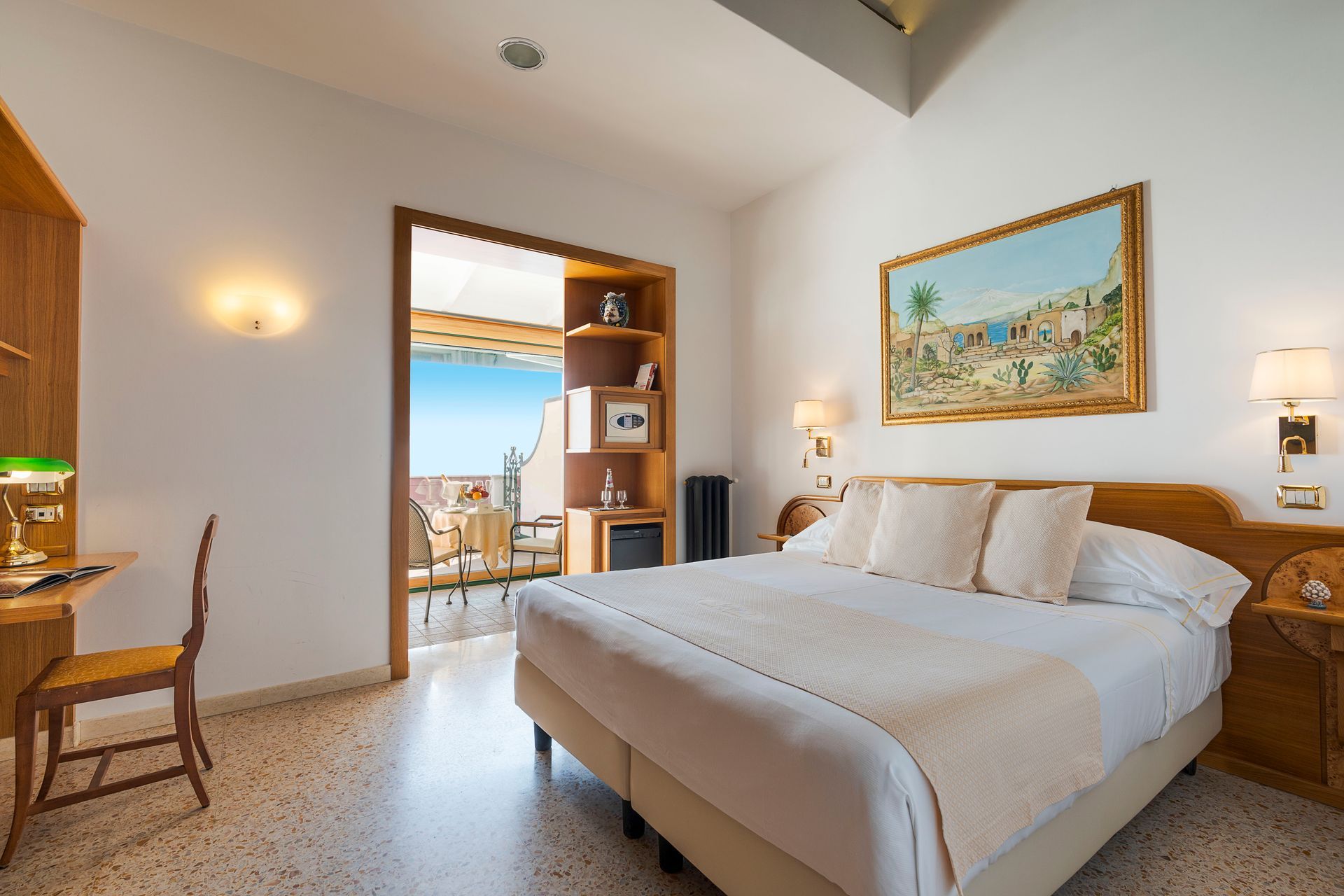Helles Hotelzimmer mit Kingsize-Bett, Gemälde, Schreibtisch und Balkonblick