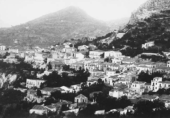 Ville de montagne en noir et blanc avec des bâtiments blancs regroupés et des montagnes en arrière-plan